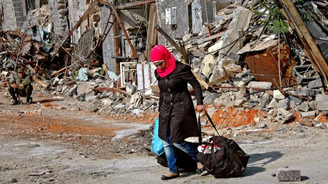 A woman carrying her belongings returns to her home in central Homs (Photo: European Pressphoto Agency)