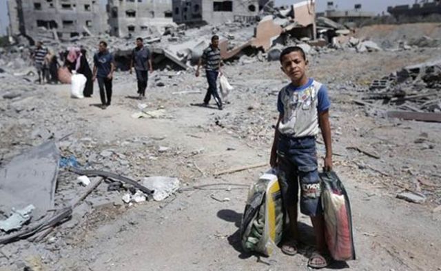A Palestinian boy carries his belongings following heavy bombardment of Gaza by Israeli forces in August 2014 (Photo: Associated Press)
