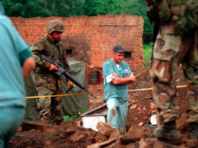 U.S. soldiers provide security as members of the Royal Canadian Mounted Police Forensics Team investigate a grave site in a village in Kosovo in 1999.  (Photo: Sgt. Craig J. Shell, U.S. Marine Corps)
