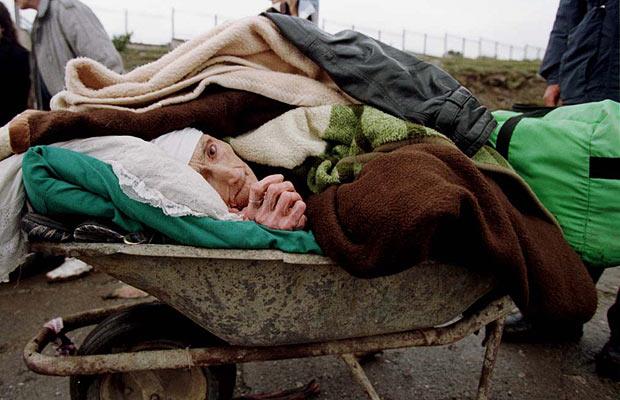 A man pushes his ailing grandmother in a wheelbarrow to Albania during the Kosovo war. 